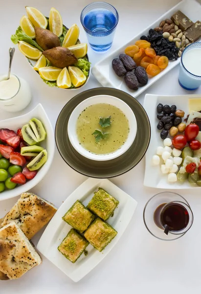 传统的斋月晚餐 Iftar 桌上有汤 面包片 干枣果 土耳其茶 新鲜水果和用汤设计的黑橄榄 免版税图库图片