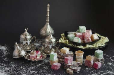 Geleneksel Türk Lokumu siyah yüzeye eski kahve fincanları ve hindistan cevizi tozlarıyla vuruyor. Kutlamaların kavramsal görüntüsü.