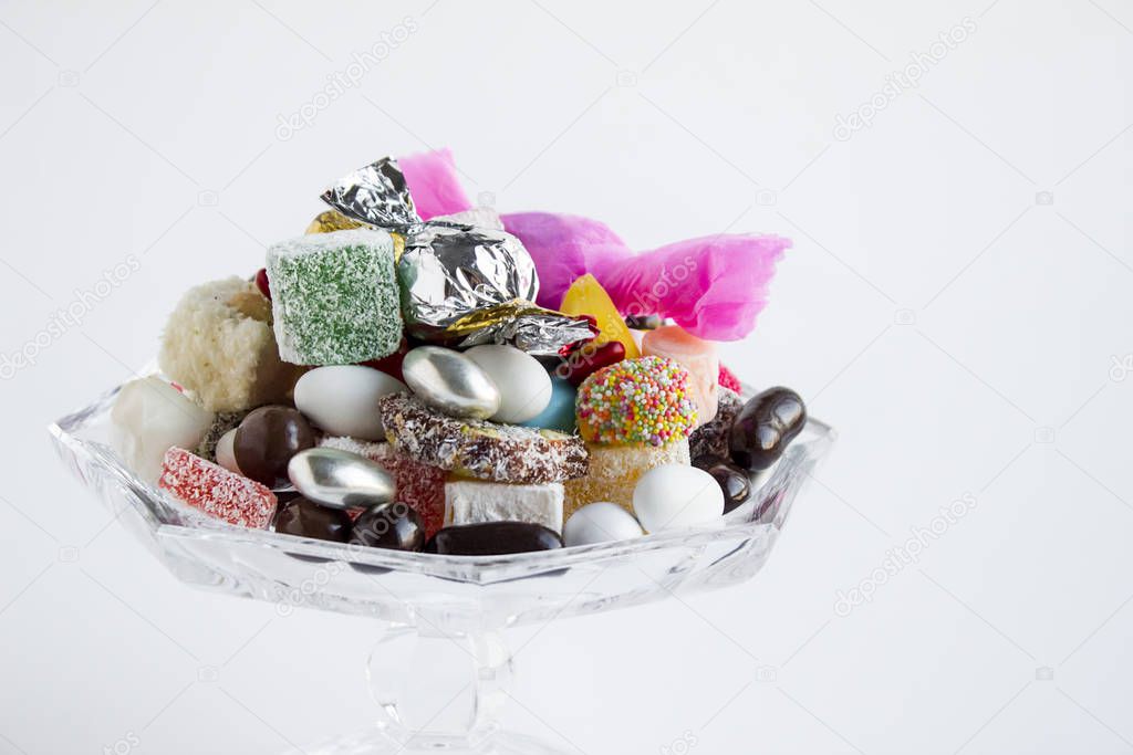 Traditional Turkish Colorful delights and candy,chocolates in the glass bowl on white with copy space.The Sugar Feast Concept or any celebration
