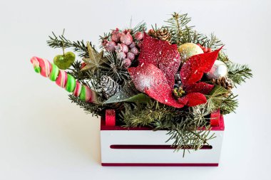 Şık, yaratıcı yeni yıl çiçekleri kırmızı noktalı, çam kozalakları ve küçük beyaz kutuda yapraklar.