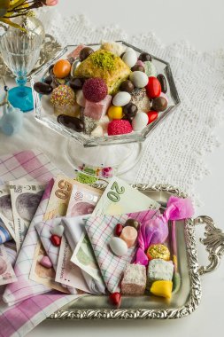close-up shot of delicious various candies in cup on white surface with money