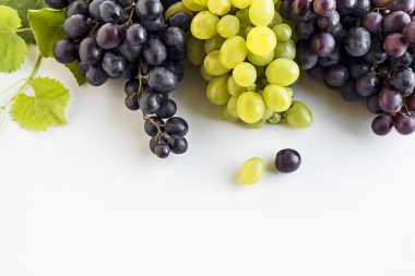 Beyaz yüzeye yakın çekim kırmızı ve yeşil üzümler