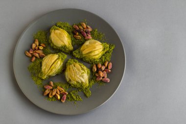 Gri arka planda fındık ve fotokopi alanı olan gri yuvarlak plakalı özel Türk baklavası..