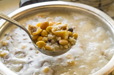 Geleneksel Tatlı Pişirme Asure, Ashura ya da Noah Pudding fırında paslanmaz çelik yemek takımı. Tenceredeki buhar malzemeleriyle dolu bir kepçeyi tutuyor..