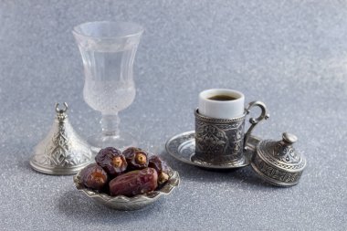 Küçük bir tabakta kahve fincanıyla kurutulmuş lezzetli hurmaların yakın plan çekimi.