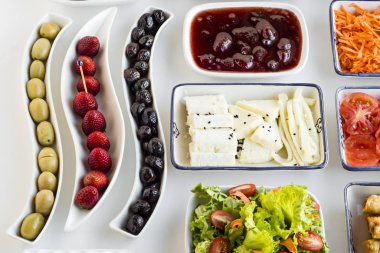 Beyaz iftar masasındaki çeşitli tabaklarda çeşitli lezzetli yiyeceklerin yakın plan çekimleri.