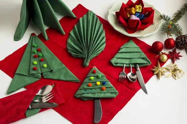 close-up shot of beautiful Christmas table setting with green napkins in various shapes