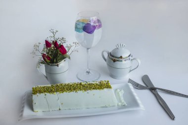 Geleneksel Türk dondurması Maras, beyaz zemin üzerindeki porselen tabakta fıstıklı dilimlenmiş çatal bıçak setiyle.