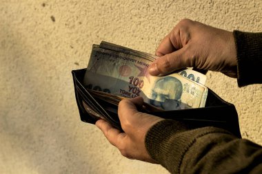 Elleri siyah deri cüzdan tutuyor ve Türk lira banknotları alıyor.