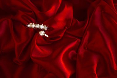Kırmızı saten kumaşlı beş taş elmas yüzük. Sevgililer Günü ya da herhangi bir özel gün konsepti..