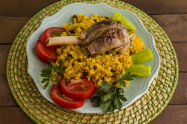 Geleneksel Arap pilavı domates, biber, maydanoz ve kuzu bacağı yuvarlak tabakta. Altında da whicker pad. Kurban Bayramı..