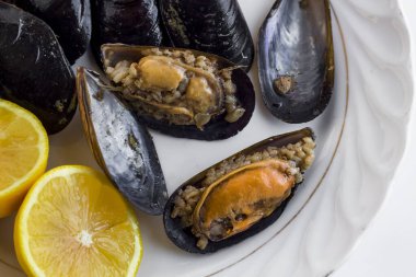 Geleneksel Türk midyeleri beyaz porselen bir tabakta taze limonla izole edilmiş. 