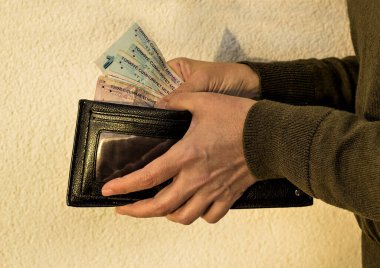 Elleri siyah deri cüzdan tutuyor ve Türk lira banknotları alıyor.