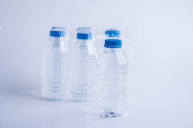 close-up shot of plastic bottles of water in transparent wrap on white surface