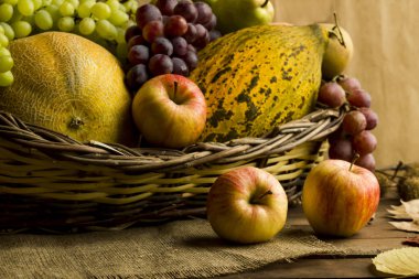 Tahta bir sepetteki kavunlar, üzümler ve elmalar. Hasat mevsiminin kavramsal görüntüsü..