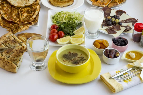 传统的斋月晚餐Iftar餐桌 传统的土耳其绿色扁豆汤和其他食物放在白色桌子上的黄色碗里 — 图库照片