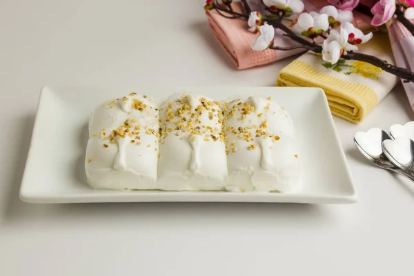 Traditional Turkish vanilla ice cream (Maras) on the white porcelain plate,topping hazelnut grains with fabric napkins on the white surface.Isolated.