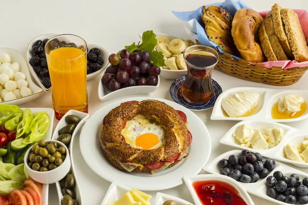 Lezzetli simitle geleneksel Türk Kahvaltısı, kızarmış yumurta, sebze, meyve ve beyaz yüzeyde taze portakal suyu.