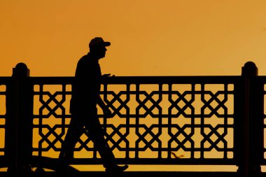 Gün batımında çitin önünde bir adamın silueti.