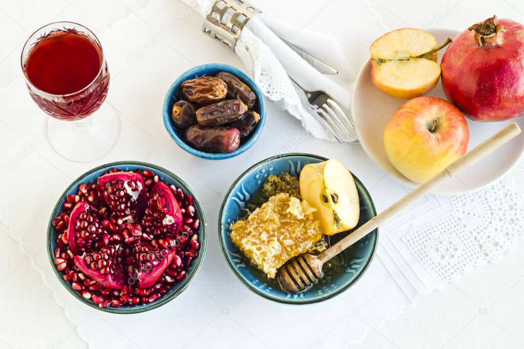 Rosh Hashanah, Traditional Jewish New Year concept with sliced apples, pomegranate,date fruit and honey on pastel blue background