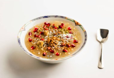 Küller (Nuh 'un Pudingi) Geleneksel Türkçe, porselen bir kasede beyaz arka planda kaşıkla İslami tatlı