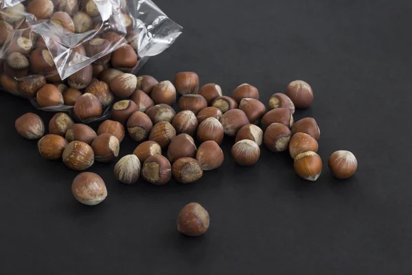 Kypsät Herkulliset Hasselpähkinät Putoavat Omasta Paketista Mustalla Pinnalla — kuvapankkivalokuva