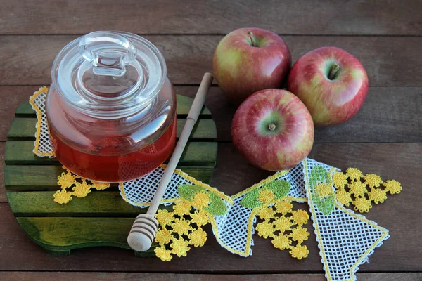 Honey,three apples and honey stick on the wooden table with handmade lace.Conceptual image of Rosh Hashanah,Jewish New Year Feast.