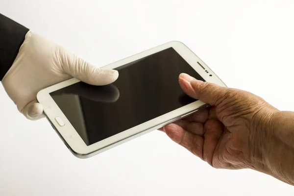 Gloved and without gloves hands holding a tablet with blank screen on white.