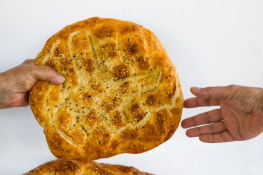 Eldivensiz iki el, beyaz arka planda ramazan ekmeği verir..