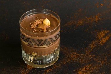 Siyah bardakta bisküvilerle kaplı kakaolu puding. Ceviz ve çikolatayla süslenmiş..