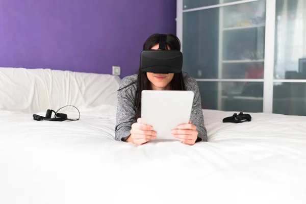 Frau mit vr auf ihrem Bett Stockbild