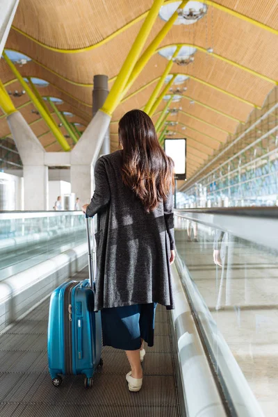 Mujer caminando en una pasarela en movimiento en un aeropuerto Fotos de stock libres de derechos