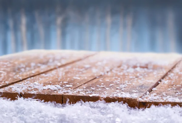 Wooden table top covered in snow with a Christmass, winter and s