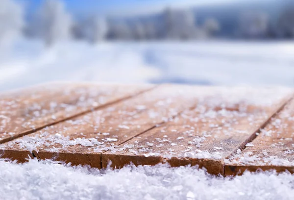 Wooden table top covered in snow with a Christmass, winter and s