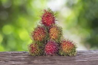  Bir ahşap zemin üzerinde taze rambutan ve doğanın bir arka plana sahiptir
