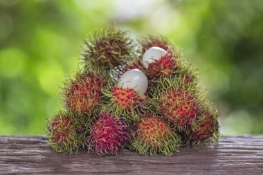  Bir ahşap zemin üzerinde taze rambutan ve doğanın bir arka plana sahiptir
