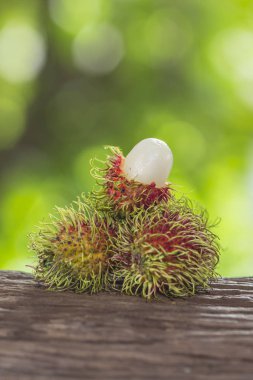  Bir ahşap zemin üzerinde taze rambutan ve doğanın bir arka plana sahiptir