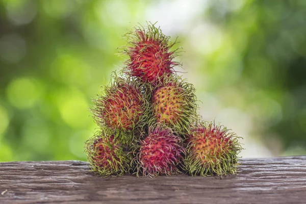 Bir ahşap zemin üzerinde taze rambutan ve doğanın bir arka plana sahiptir