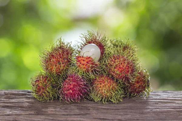 Färsk rambutan på ett trägolv och har en bakgrund av naturen — Stockfoto