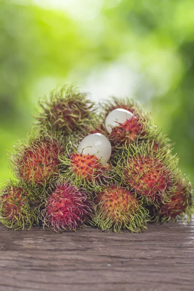 Färsk rambutan på ett trägolv och har en bakgrund av naturen — Stockfoto