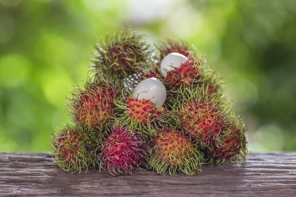  Bir ahşap zemin üzerinde taze rambutan ve doğanın bir arka plana sahiptir