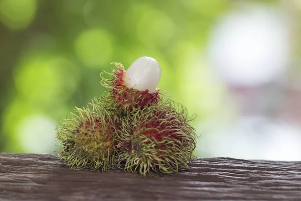  Bir ahşap zemin üzerinde taze rambutan ve doğanın bir arka plana sahiptir