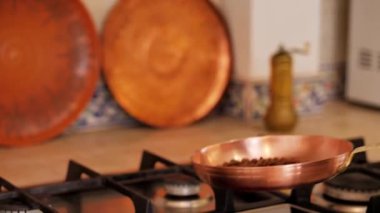 Girl toss and roast coffee beans in a copper skillet