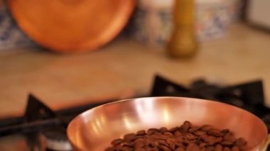 Girl toss and roast coffee beans in a copper skillet