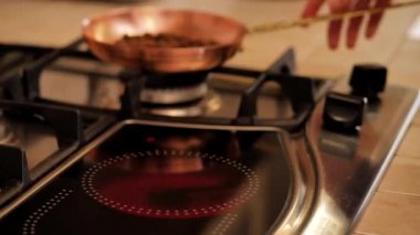 Girl puts on the plate the pan with coffee beans. Kitchen stove.