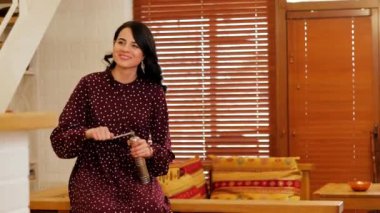 Young girl in polka dot dress smiles and coffee grinds in a coffee grinder.