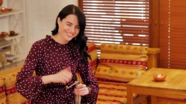Young girl in polka dot dress smiles and coffee grinds in a coffee grinder.