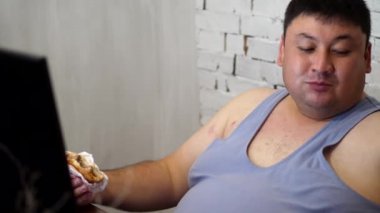 Fat man eating a Burger with fries and laughs