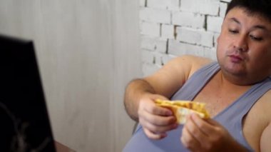 Fat man eating a pizza with sauce