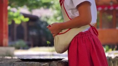 A young girl pours dogwood berries from the apron to the tray